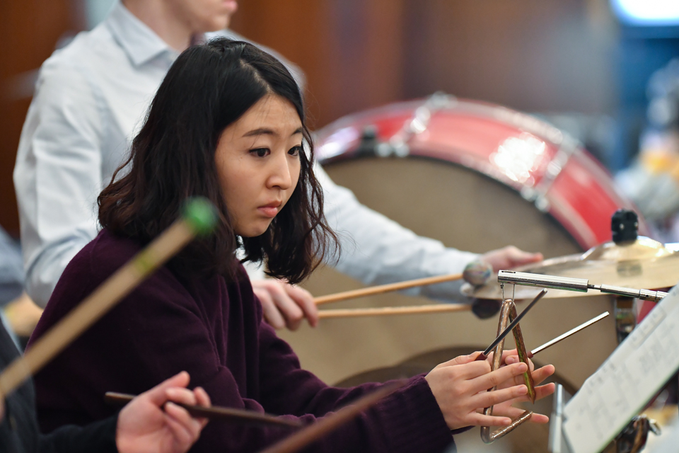 A student playing the triangle in the percussion section of the RCM Philharmonic